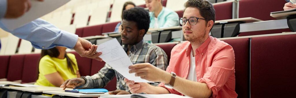 teacher giving tests to students at lecture education, high school, university, learning and people concept - teacher giving tests to students at lecture