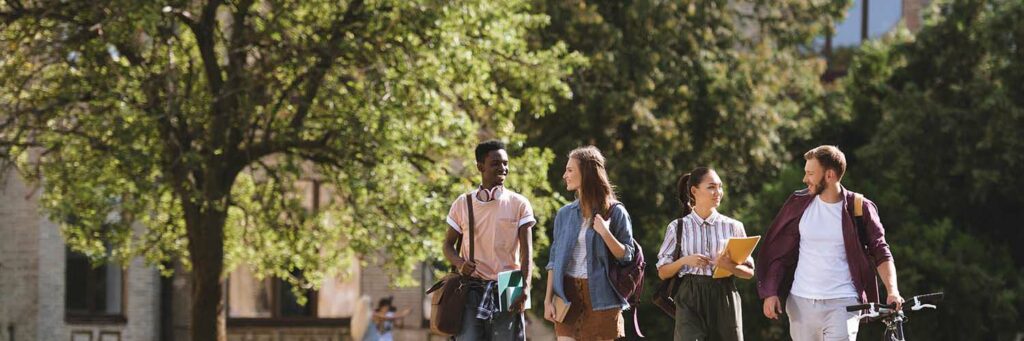 Four college students walking with their backpacks on campus