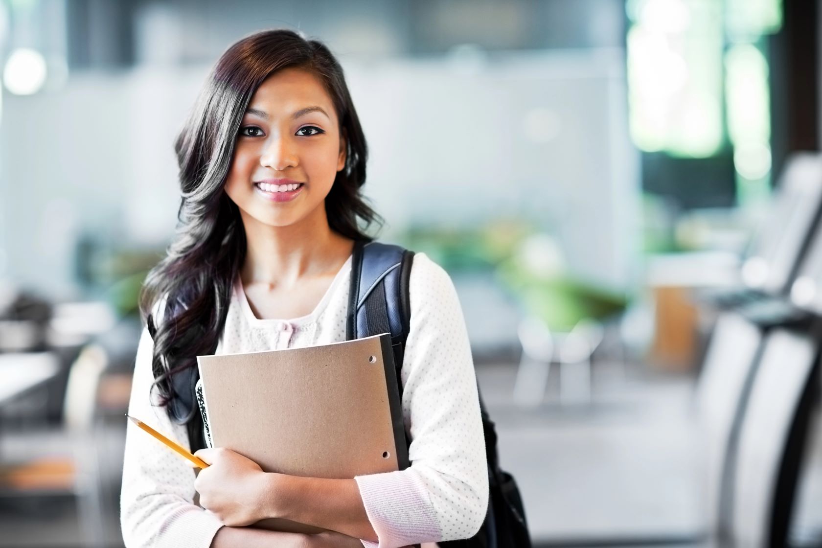 Female student with a backpack holding a folder.