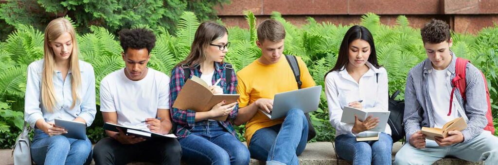 Preparing for lecture. Teens sitting in university campus with books and devices