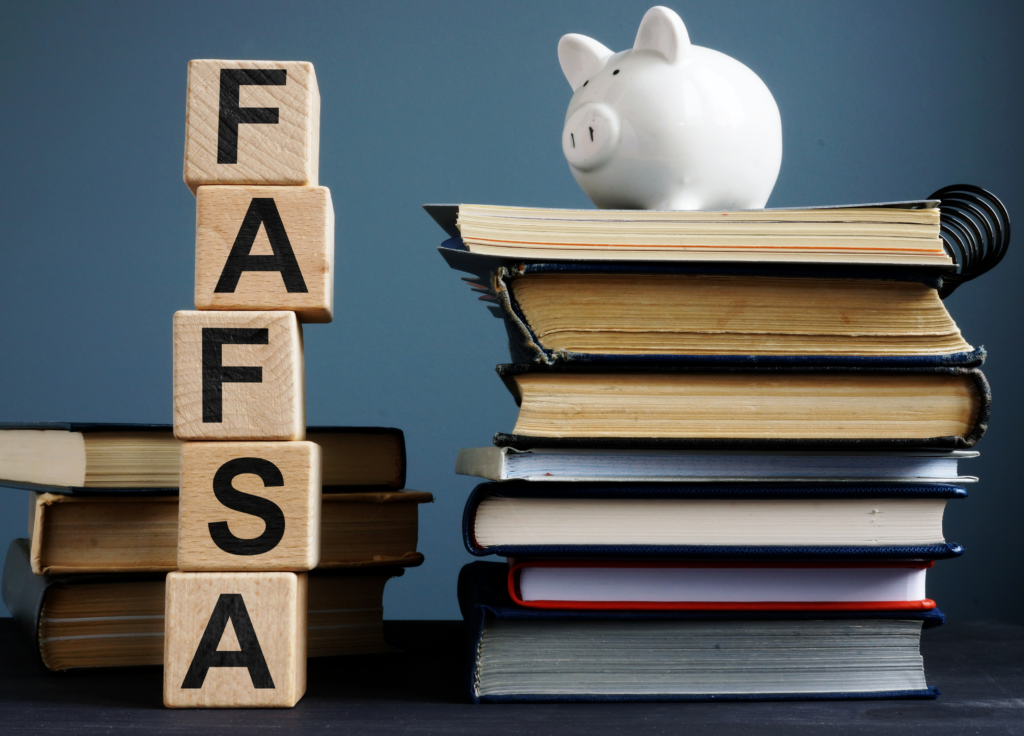 FAFSA spelled out with blocks and stack of books with a piggy bank on top.