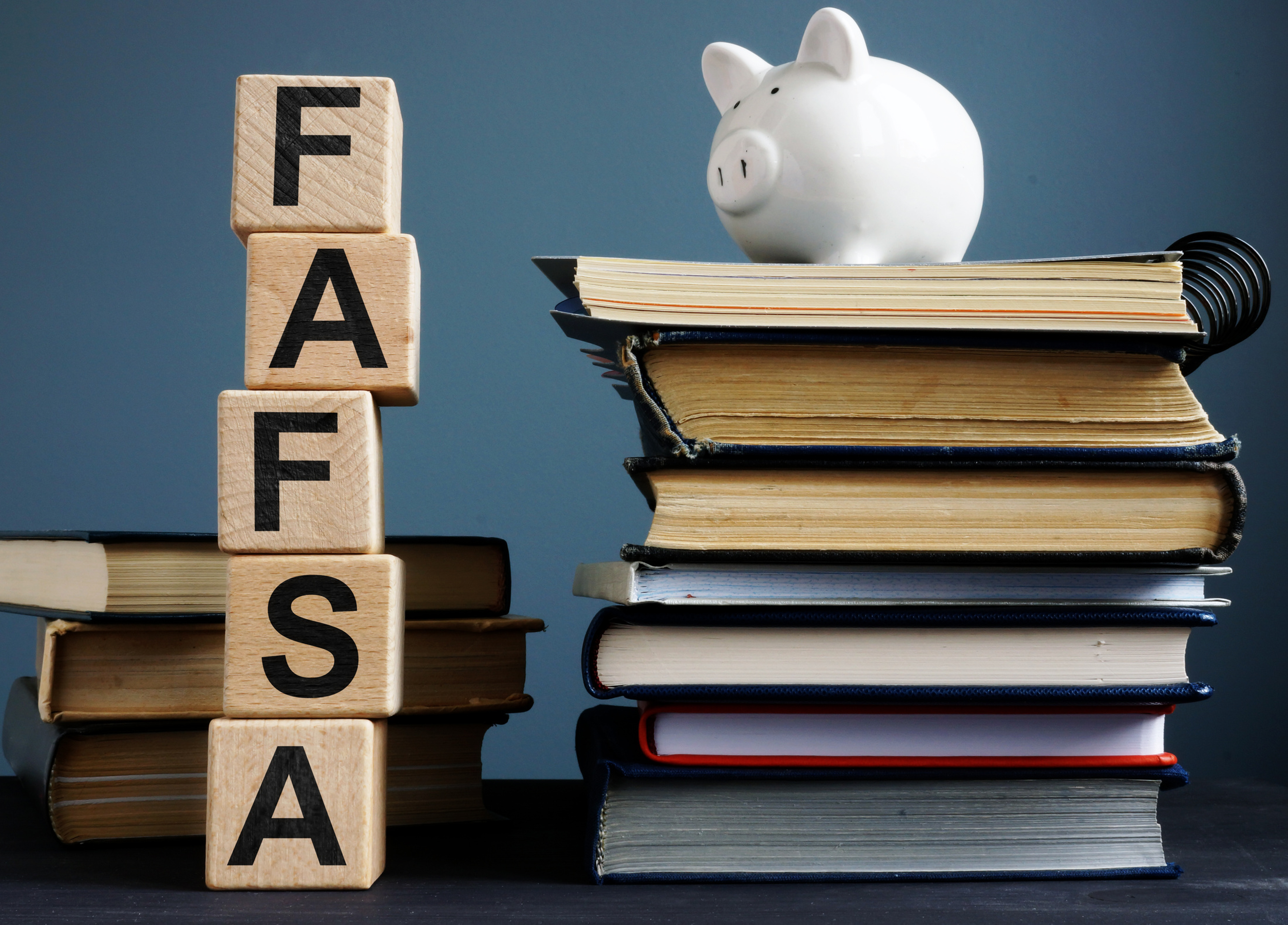 FAFSA spelled out with blocks and stack of books with a piggy bank on top.