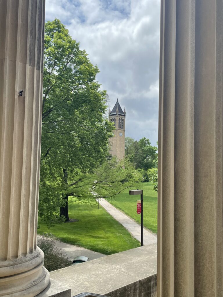 View between two columns with a tree and a watch tower in the background at Iowa State University