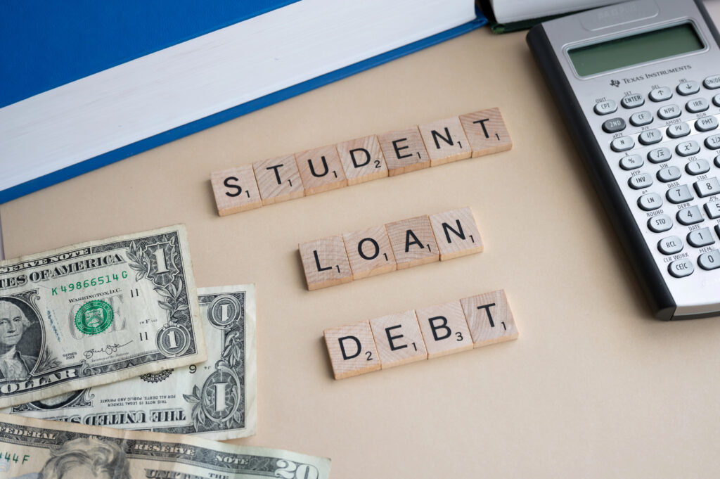 Tiles spelling Student Loan Debt. Cash bills and a calculator.